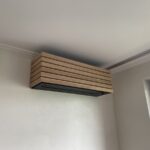 Nástěnná klimatizační jednotka s dřevěným lamelovým krytem v interiéru