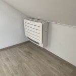 Bílá vnitřní klimatizační jednotka umístěná nízko na stěně